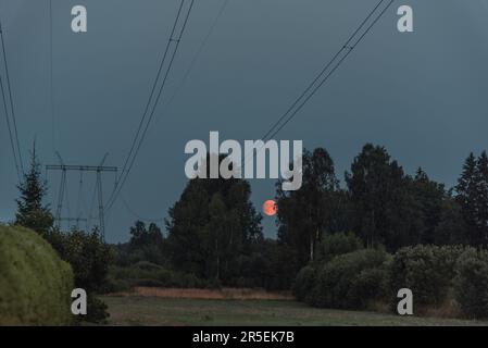 Montée pleine lune dans la campagne sous les fils électriques Banque D'Images