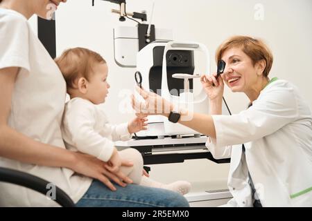 Ophtalmologiste effectuant un dépistage de la vision chez l'enfant lors de la consultation initiale Banque D'Images