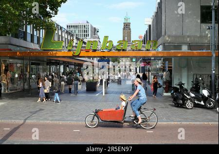 Un cycliste sur une piste cyclable cargo passe devant le quartier commercial de Lijnbaan à Rotterdam, aux pays-Bas. Banque D'Images