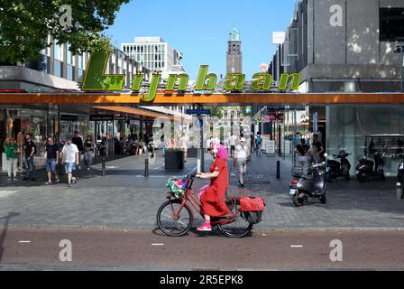 Cycliste sur une piste cyclable passant par le quartier commerçant de Lijnbaan à Rotterdam, aux pays-Bas Banque D'Images