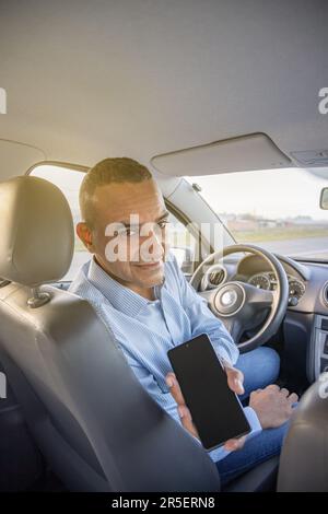 Le conducteur montre l'écran de son téléphone portable dans sa voiture. Banque D'Images