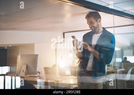 J'ai fait ici pour que je puisse maintenant réserver mon trajet à la maison. un homme d'affaires utilisant son téléphone portable tout en se tenant dans son bureau. Banque D'Images