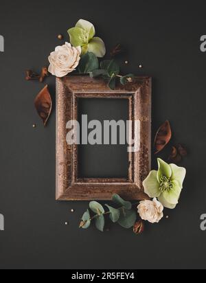 Composition automne-hiver avec cadre vintage, feuilles séchées, écorce d'arbres et baies sur fond sombre. Flat lay, espace de copie. Banque D'Images