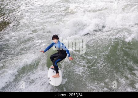 Surfeurs à la vague artificielle Eisbach sur la rivière Isar qui coule à travers le parc Englischer Garten (jardins anglais) à Munich en Allemagne Banque D'Images