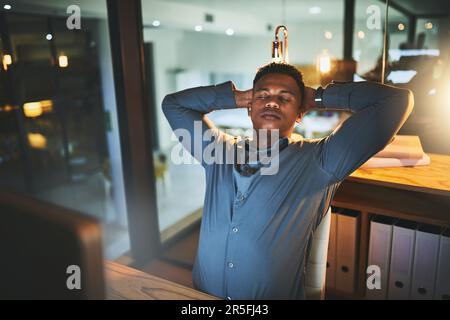 Se sentir détendu maintenant que le travail est fait. un beau jeune homme d'affaires qui a l'air détendu en travaillant tard dans la nuit dans un bureau moderne. Banque D'Images