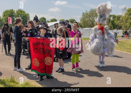 Cambridge, Royaume-Uni. 3 juin 2023. Scène de défilé colorée à Strawberry Fair 2023, Cambridge. Les participants dans des costumes élaborés célèbrent la créativité locale et l'esprit communautaire. Un enfant tient une bannière rouge indiquant « FRAISE FAIR » au milieu de tenues théâtrales et fantastiques. Tentes blanches et parc vert visibles en arrière-plan. La Foire aux fraises de 2023. Penelope Barritt/Alamy Live News Banque D'Images