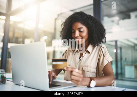 Gérer son entreprise à crédit. une jeune femme d'affaires utilisant une carte de crédit et un ordinateur portable dans un bureau moderne. Banque D'Images