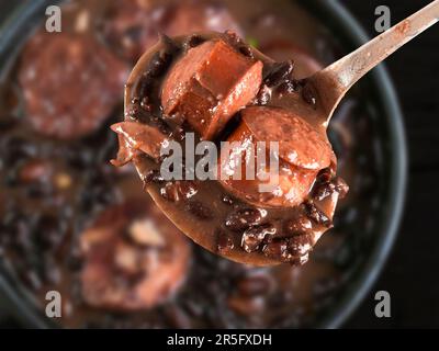 Concentration sélective sur la cuillère avec la nourriture brésilienne Feijoada. Cuisine brésilienne traditionnelle faite avec des haricots noirs. Banque D'Images
