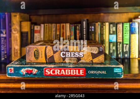Un jeu d'échecs repose sur une boîte de Scrabble devant une étagère de romans policiers et d'aventures dans la maison Huntingdon sur le domaine de Satemwa près de Thyolo, au Malawi. La maison d'hôtes a été construite vers 1935 et ne compte que cinq chambres. Banque D'Images