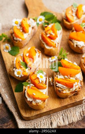 Planche à découper avec abricot maison sur bruschetta au fromage à la crème vegan. Banque D'Images