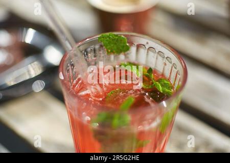 Un verre de mojito aux fraises est servi dans un café en plein air. Cocktail d'été frais et froid avec fraises, sirop et feuilles de menthe Banque D'Images