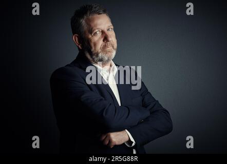 Je suis né pour le monde de l'entreprise. Portrait studio d'un beau homme d'affaires mature debout avec ses bras repliés sur un fond sombre. Banque D'Images