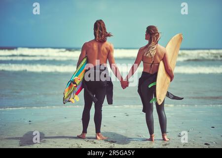 La vague parfaite est là, allez la trouver. Vue arrière d'un jeune couple en attente de la vague parfaite. Banque D'Images