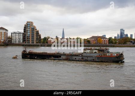 Londres, Royaume-Uni - 23 octobre 2020 : une grande péniche abandonnée est amarrée sur la Tamise en attendant son destin. En arrière-plan se trouve la ligne d'horizon de Londres. Banque D'Images