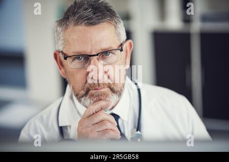 Votre bien-être est la priorité numéro un. Portrait d'un médecin mature utilisant un ordinateur à un bureau dans son bureau. Banque D'Images