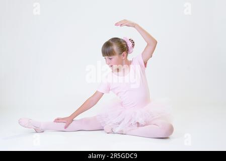 Petite danseuse de ballerine dans un étudiant rose de tutu academy posant sur fond blanc Banque D'Images