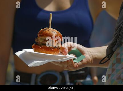 Un visiteur du marché agricole tient un hamburger frais sur un plateau de papier Banque D'Images