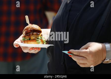 Un visiteur du marché agricole tient un hamburger frais sur un plateau de papier Banque D'Images