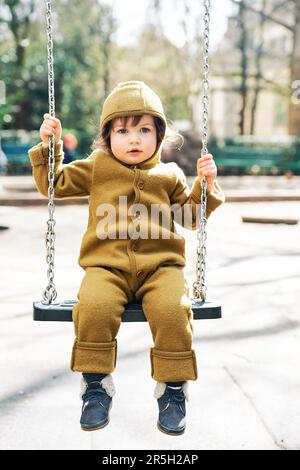 Portrait en plein air d'un enfant en bas âge qui s'amuse sur le terrain de jeu, portant une combinaison chaude Banque D'Images