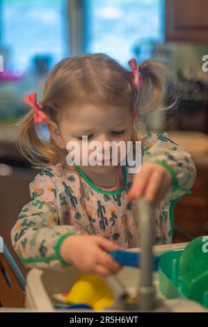 Petite fille jouant avec le lave-vaisselle Banque D'Images