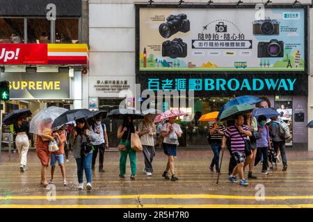 Gens ordinaires de Hong Kong traverser Une route pendant Un orage , Causeway Bay, Hong Kong, Chine. Banque D'Images