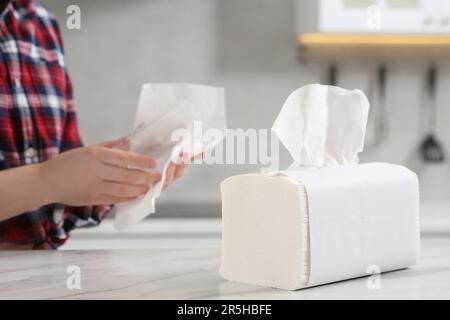 Femme essuyant le verre avec une serviette en papier à la table en marbre blanc dans la cuisine, foyer sélectif. Espace pour le texte Banque D'Images