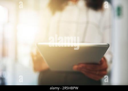 Travailler avec son booster de productivité préféré à portée de main. Gros plan d'une femme d'affaires méconnue utilisant une tablette numérique dans un bureau. Banque D'Images