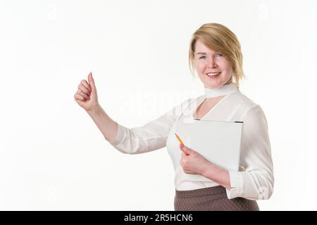 Femme d'affaires souriante et confiante montrant les pouces, tenant le presse-papiers et le crayon entre les mains. Portrait d'une femme d'affaires mûre regardant l'appareil photo Banque D'Images