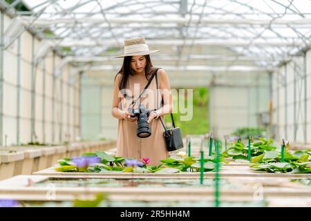 Une femme asiatique photographie des nénuphars à l'intérieur d'une serre à Mae Rim, Chiang Mai, dans les jardins botaniques Queen Sirikit. Banque D'Images