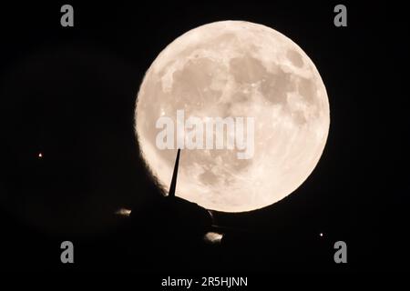 Londres, Royaume-Uni. 03rd juin 2023. Un avion de ligne passager passe la pleine lune également connue sous le nom de June's Strawberry Moon au-dessus de Twickenham à Londres. Crédit : SOPA Images Limited/Alamy Live News Banque D'Images