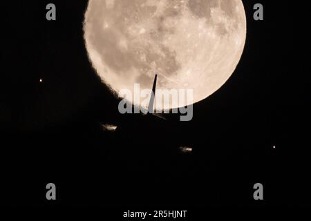 Londres, Royaume-Uni. 03rd juin 2023. Un avion de ligne passager passe la pleine lune également connue sous le nom de June's Strawberry Moon au-dessus de Twickenham à Londres. Crédit : SOPA Images Limited/Alamy Live News Banque D'Images
