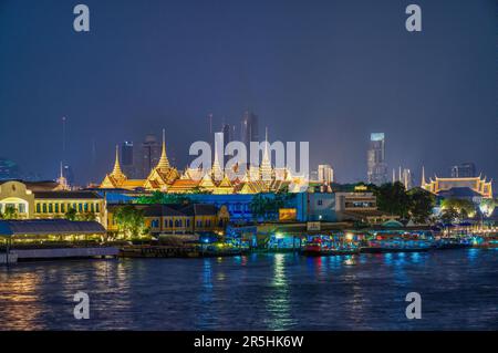 Rayonnant d'une lueur d'or, le Grand Palais émerge de l'arrière des boutiques animées et des jetées de bateaux le long de la rivière Chao Phraya. Banque D'Images