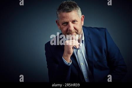 J'ai perdu toute ambition. Portrait studio d'un homme d'affaires confiant et mature assis avec sa main sur son menton sur un fond sombre. Banque D'Images