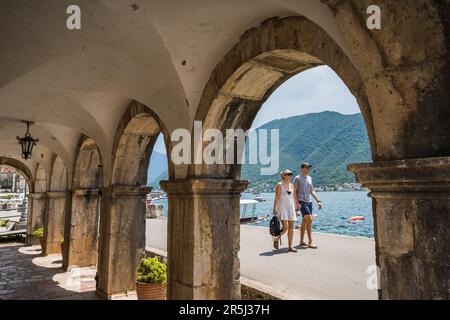 Un couple adulte photographié au soleil en mai 2023, marchant le long de la promenade et du bord de l'eau à Perast, au Monténégro. Banque D'Images