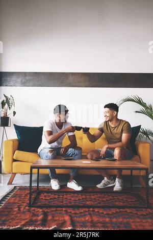 Santé à nous devenir caféiné. deux jeunes hommes partagent un toast tout en étant assis dans un café. Banque D'Images