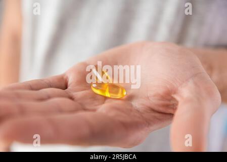 Capsules d'huile de poisson avec oméga-3, vitamine D dans la main mâle. Supplément nutritionnel, médicaments, médicaments pour les soins de santé. Banque D'Images