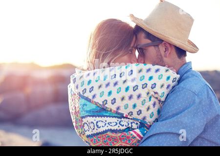 L'amour nous tiendra au chaud. un jeune couple affectueux à la plage. Banque D'Images