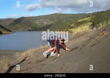 Adolescent jouant sur les dunes de sable du lac Wainamu à Bethells Beach. Auckland. Banque D'Images