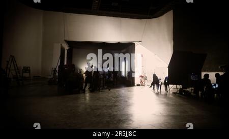 Des images floues de l'équipe de tournage travaillant et filmant dans un studio de production vidéo utilisant des équipements tels que la caméra de cinéma, la lumière de grand film et la boîte souple ou Banque D'Images