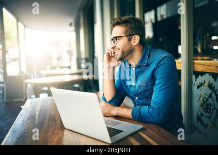 Conclure la vente par téléphone. un beau jeune homme d'affaires assis seul et parlant sur son téléphone portable dans un café. Banque D'Images