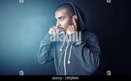 Un peu de battements pour le motiver. Photo en studio d'un jeune sportif debout sur un fond sombre. Banque D'Images