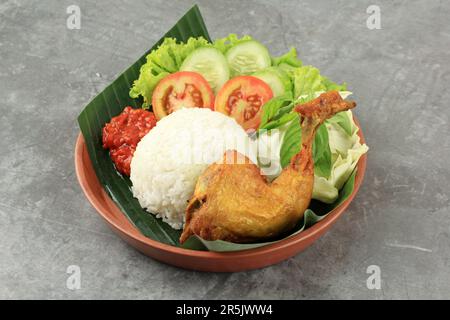 Pecel Ayam ou Nasi Ayam Goreng avec Sambal Terasi, Fried Chiken avec riz et sauce épicée. Cuisine populaire indonésienne de rue Banque D'Images