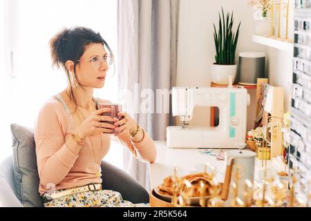 La créatrice de bijouteries a bu un café du matin dans son studio de travail Banque D'Images