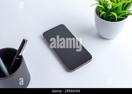 Téléphone sur le bureau. Plante et stylos peut à côté. Affichage vide pour la présentation de l'application. Moderne, composition d'entreprise Banque D'Images