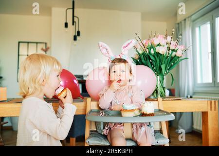 Deux enfants amusants mangeant des cupcakes, petite fille célébrant son premier anniversaire avec son petit frère Banque D'Images