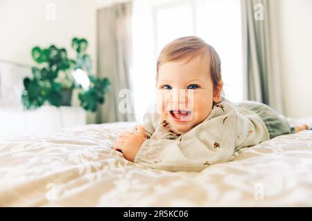 Portrait intérieur d'une petite fille qui rit sur le lit de ses parents Banque D'Images