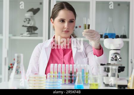 Un jeune scientifique de laboratoire examine les tubes à essai avec du pétrole brut Banque D'Images