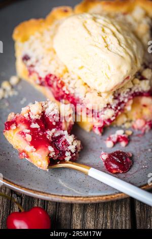 Tarte à la crème de cerise aigre, pâtisserie à la crème et miettes, servie avec de la crème glacée à la vanille. Ambiance et décoration rustiques et moody. Banque D'Images