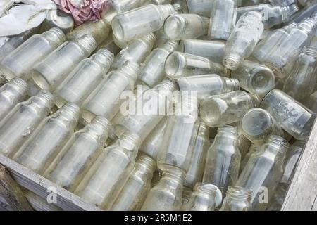 Bouteilles en verre vides utilisées stockées pour recyclage, mise au point sélective. Banque D'Images