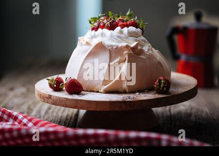 Gâteau Pavlova décoré de fraises sur une table rustique en bois. Le gâteau est fait de meringue et de crème fouettée Banque D'Images